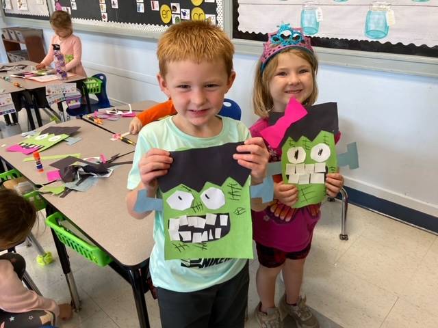 2 students showing completed green monster face craft