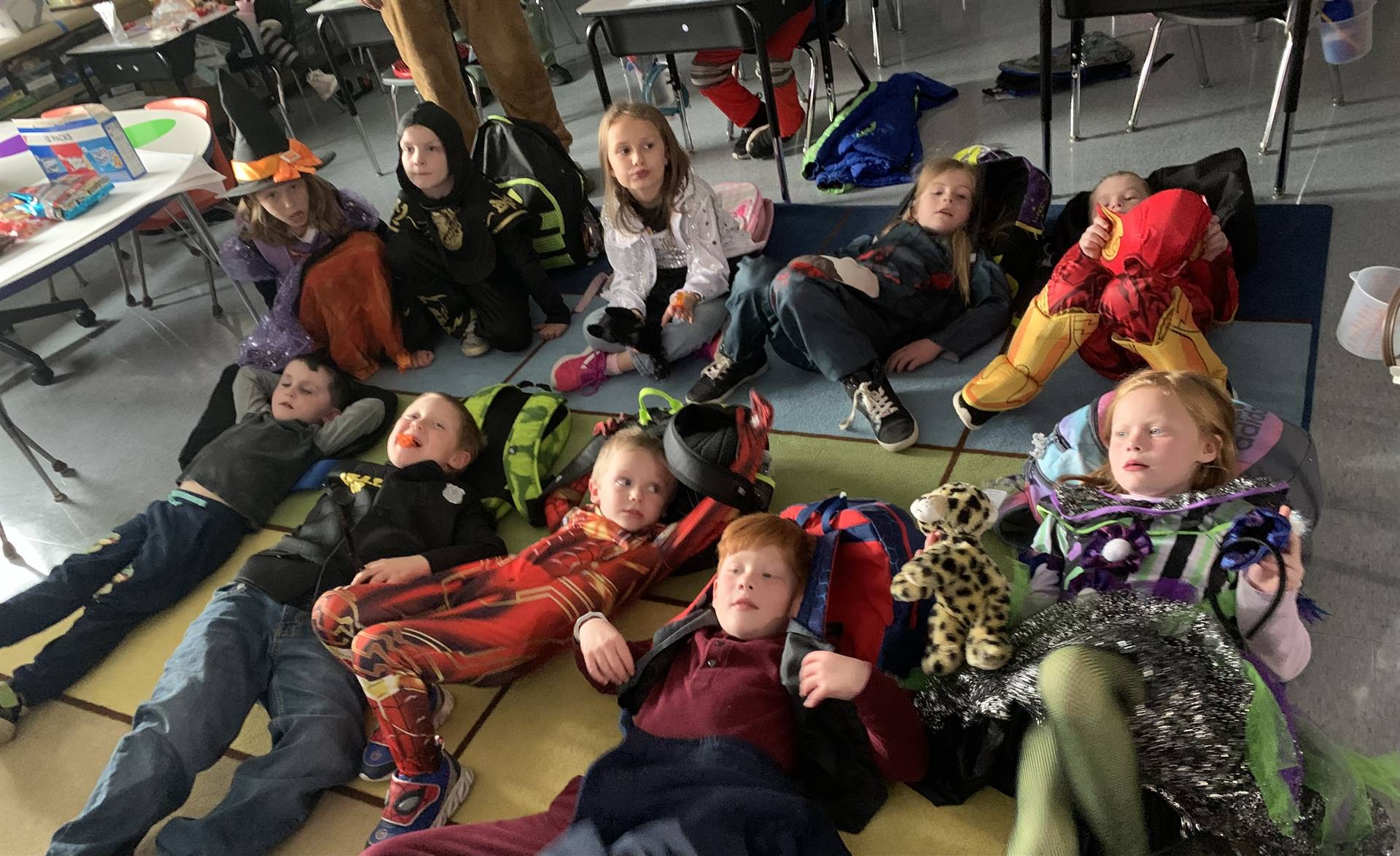 a group of students in various halloween costumes relaxing on the floor