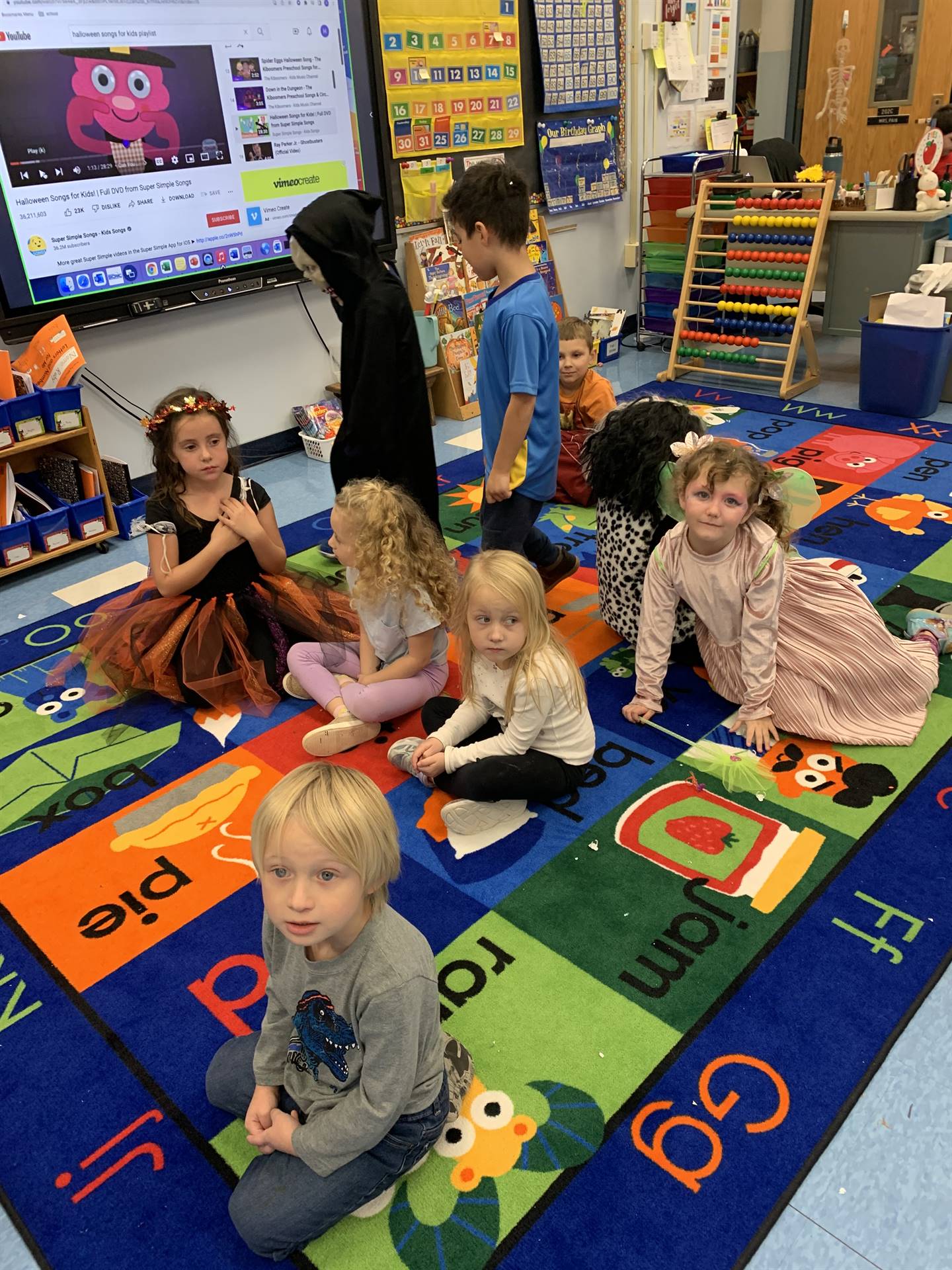 students dressed up in halloween costumes on a bright colored rug