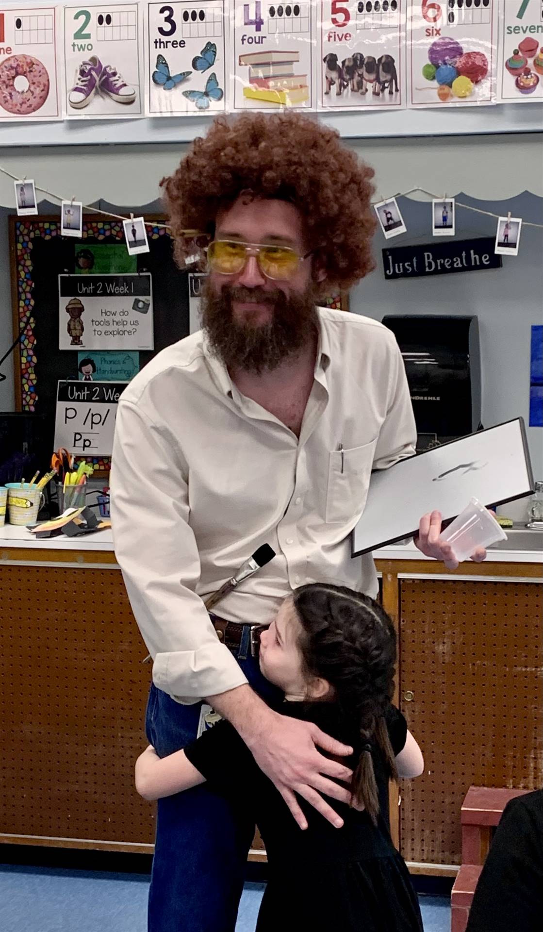A teacher as Bob Ross, the happy painter hugging a student.