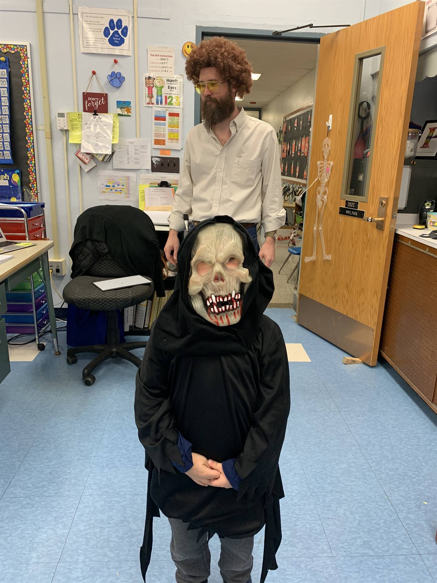 a student dressed up with painter bob ross behind him