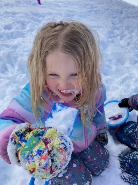 a student with a "snow mustache"  licks a snowball