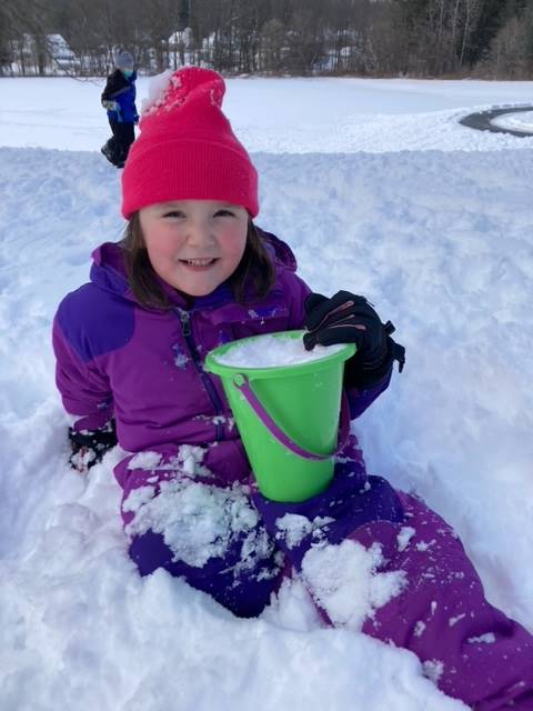 a student holding a bucket and sitting in snow