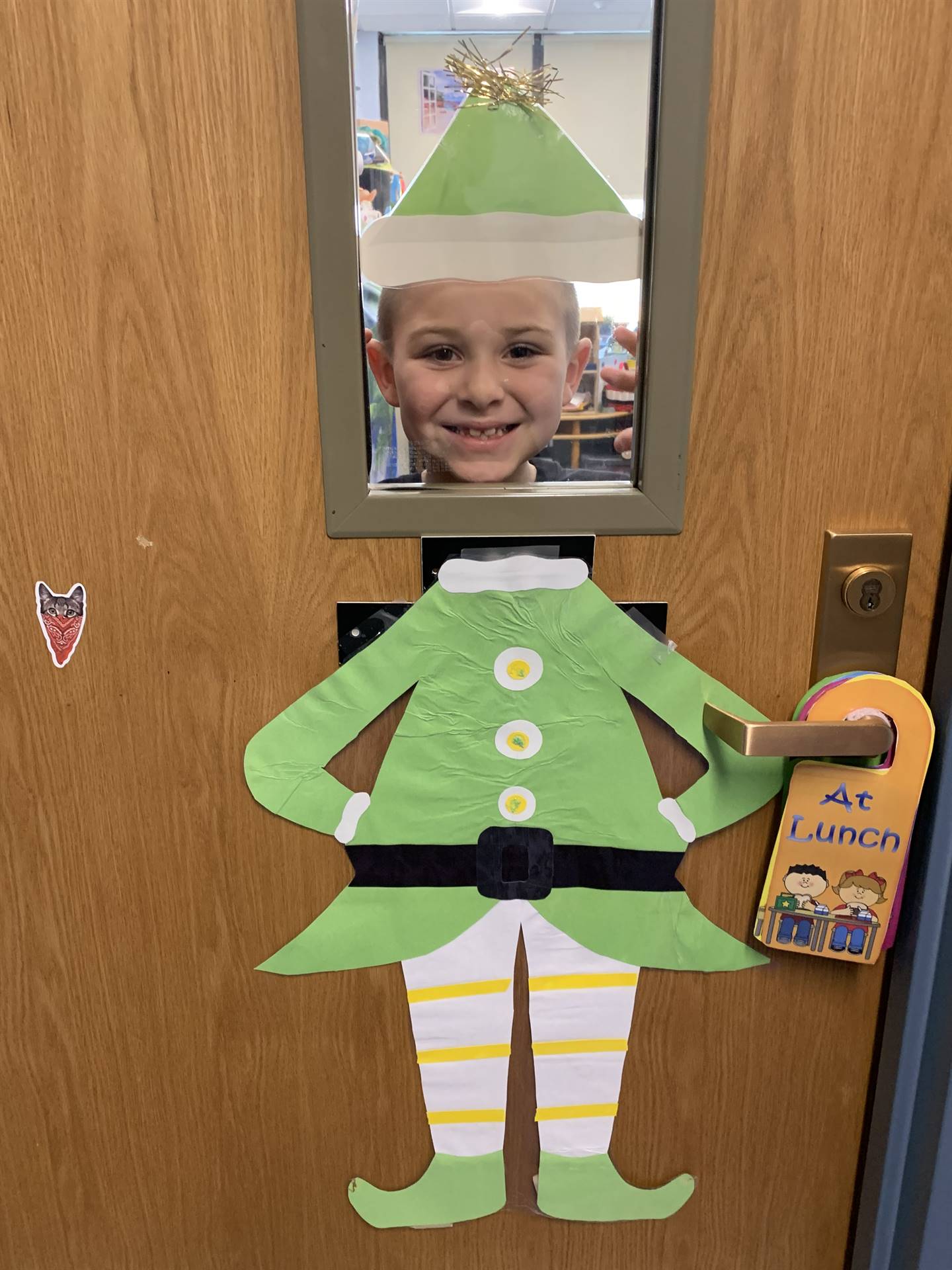 student with green elf suit on peeking through the window.