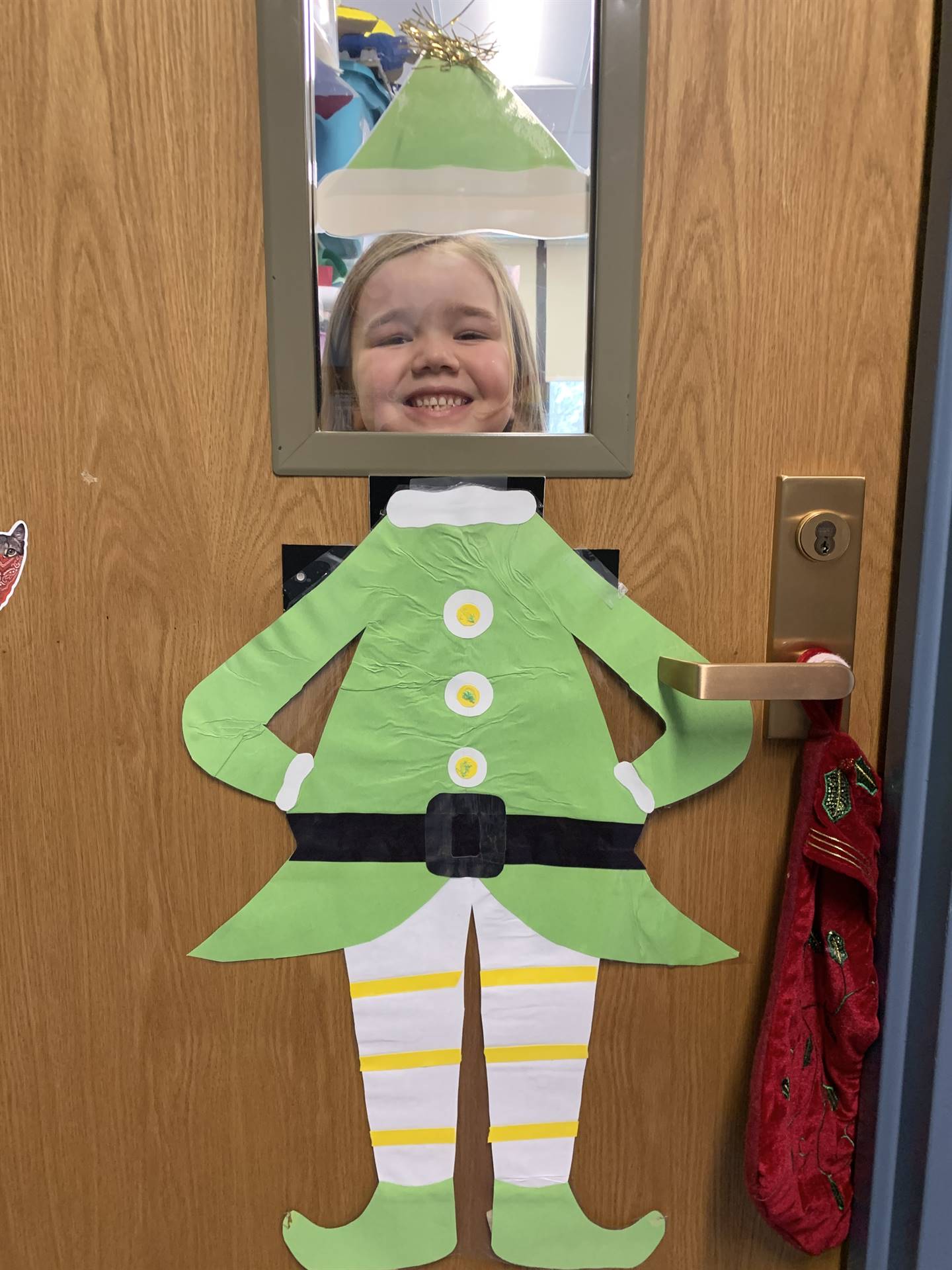 student with green elf suit on peeking through the window.