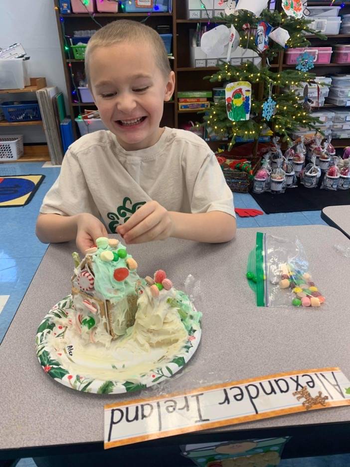 a student decorates a gingerbread house.