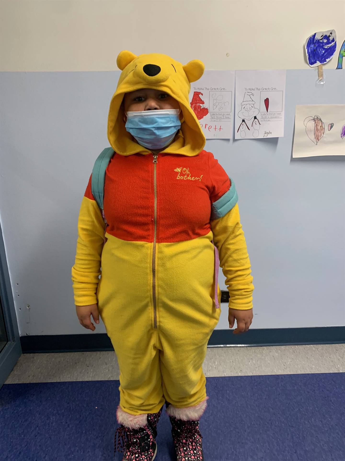 Child dressed in winnie pooh pajamas. Yellow with red top.