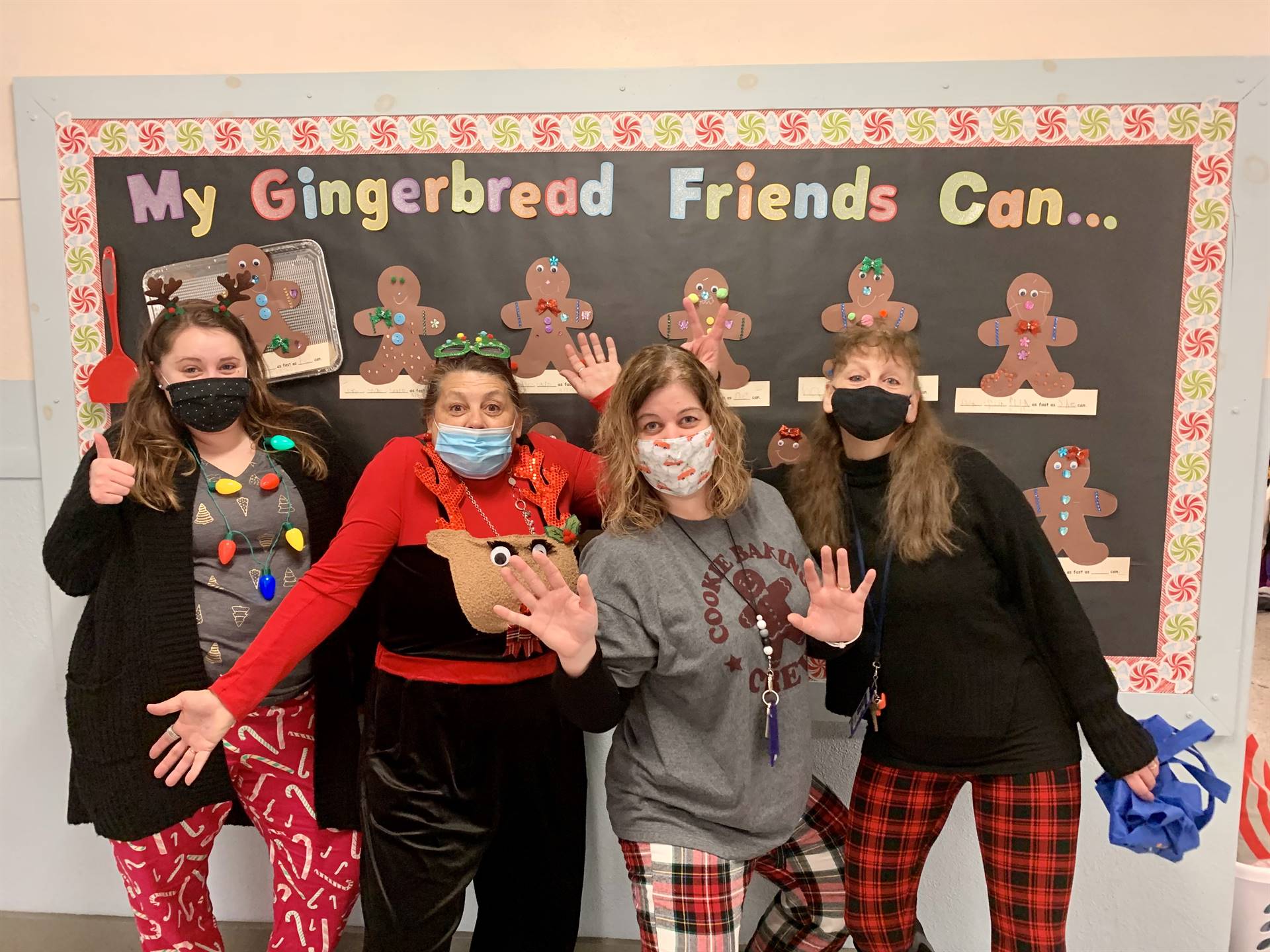 4 teachers standing with bulletin board background with gingerbread friends. 