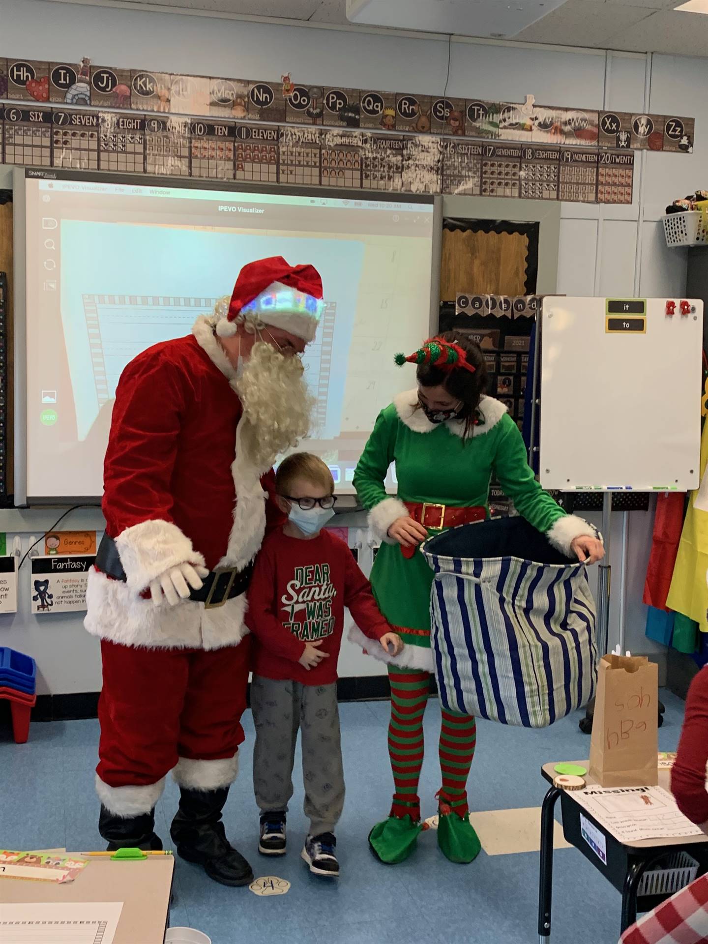 A student poses between Santa and Elf. 