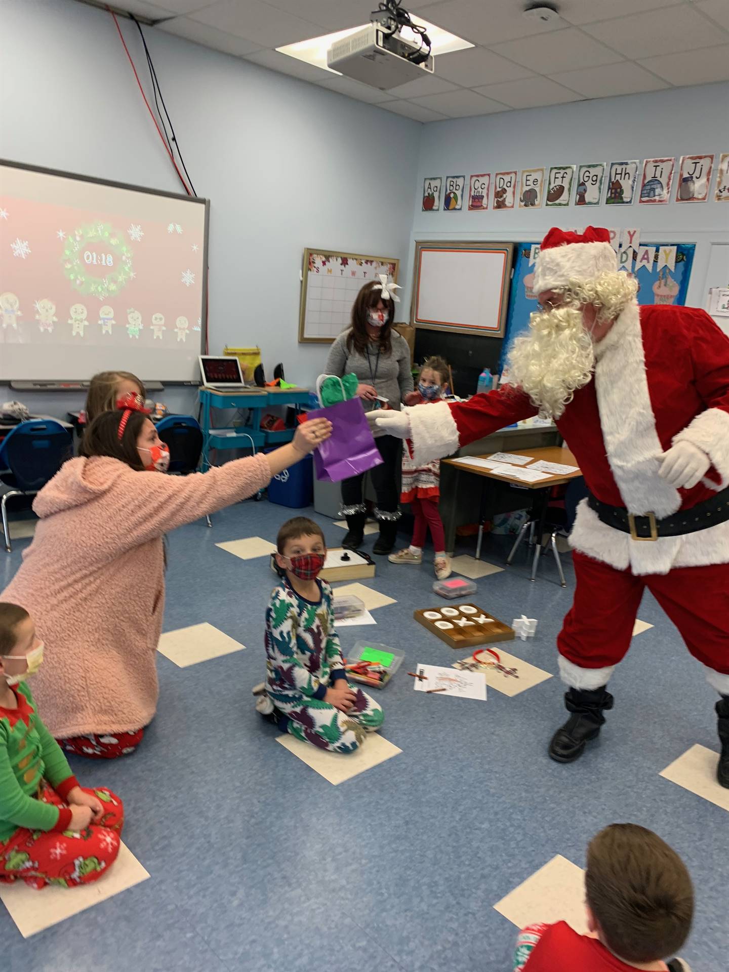 a teacher holds out arm to accept Santa's gift. 