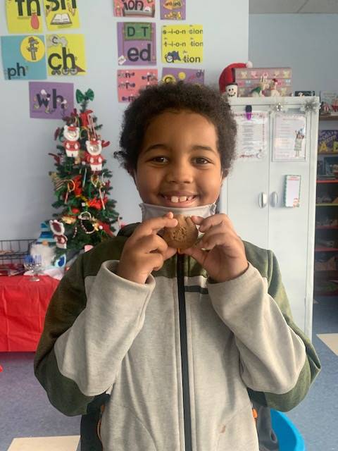 student smiling with playdo gingerbread friend. 