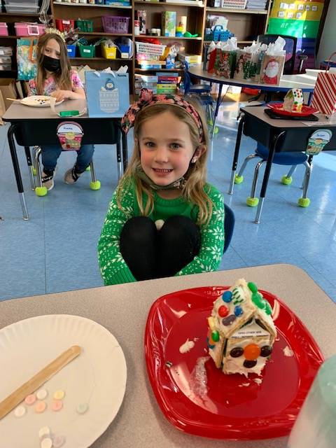 student with decorated gingerbread house. 