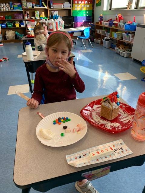 student tasting frosting from gingerbread house decorating.