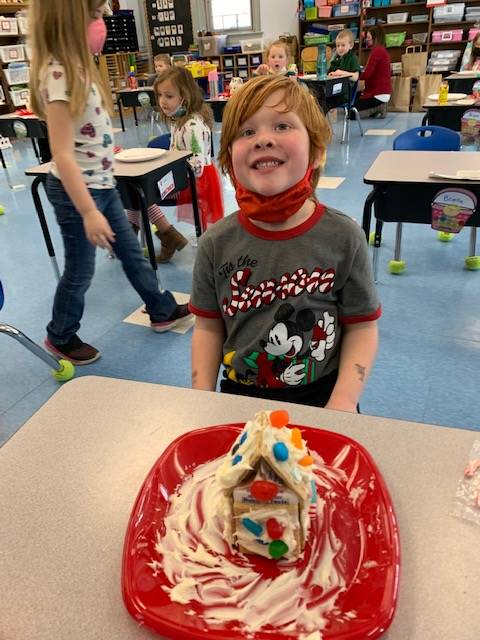 student with decorated gingerbread house. 