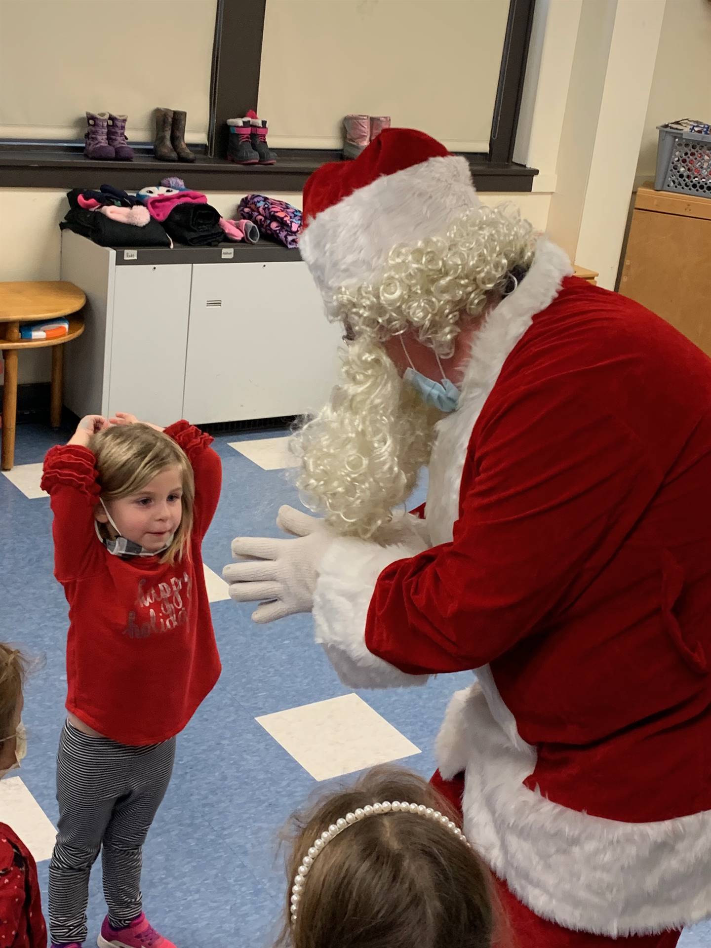 Santa speaks to student who is holding hands over head. 
