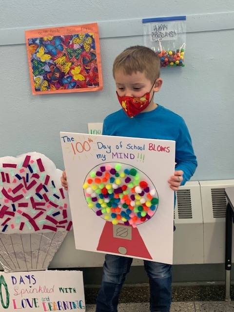 student holding an art project of gumboil machine with 100 gumballs of all colors