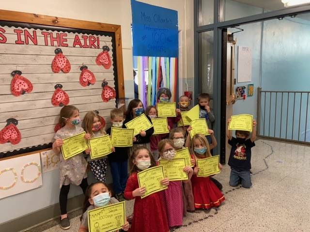 A class of students holding up certificates stating they are 100days smarter