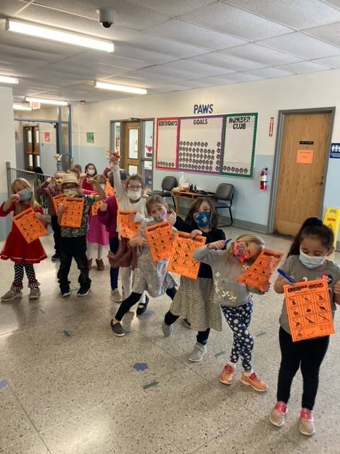 students holding orange paper showing a 100th day project
