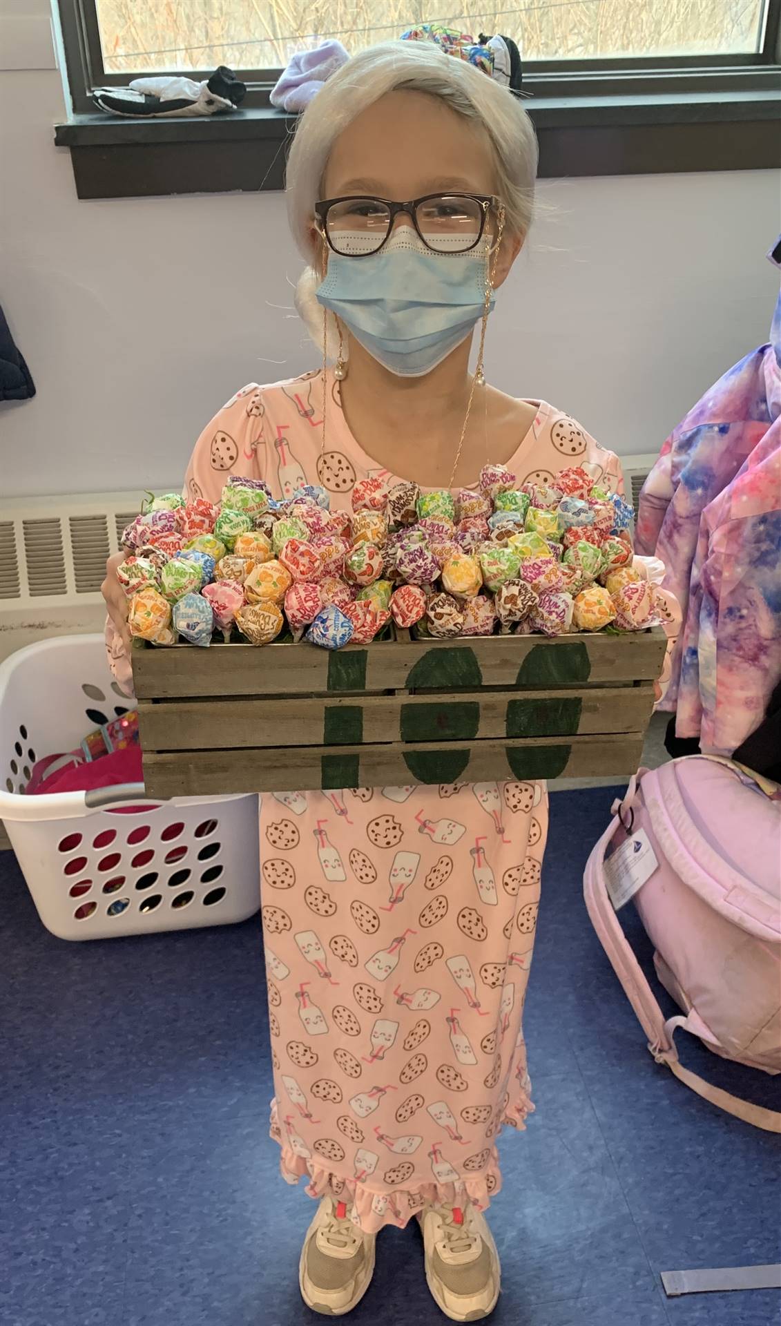 a student dressed as 100 years old and holding 100 lollipops.