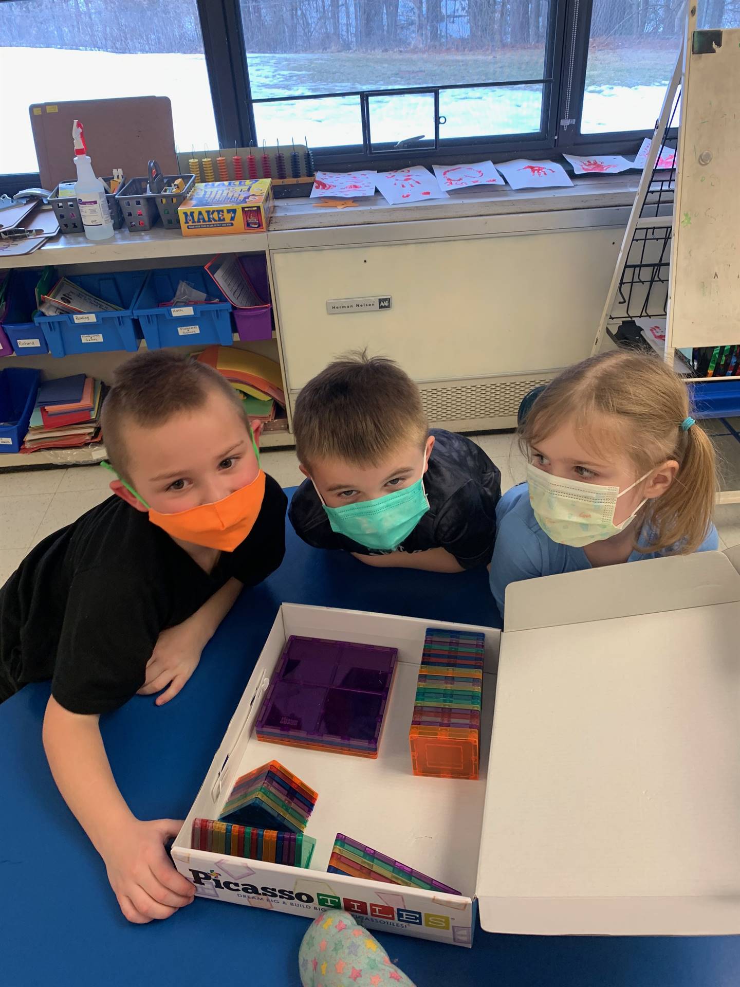 3 students putting colorful magnetic pieces back in the box!
