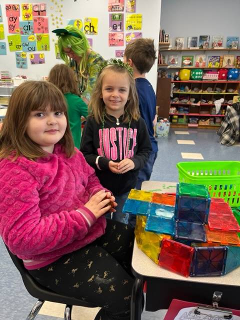 2 students with a multicolored magnetic tile structure.