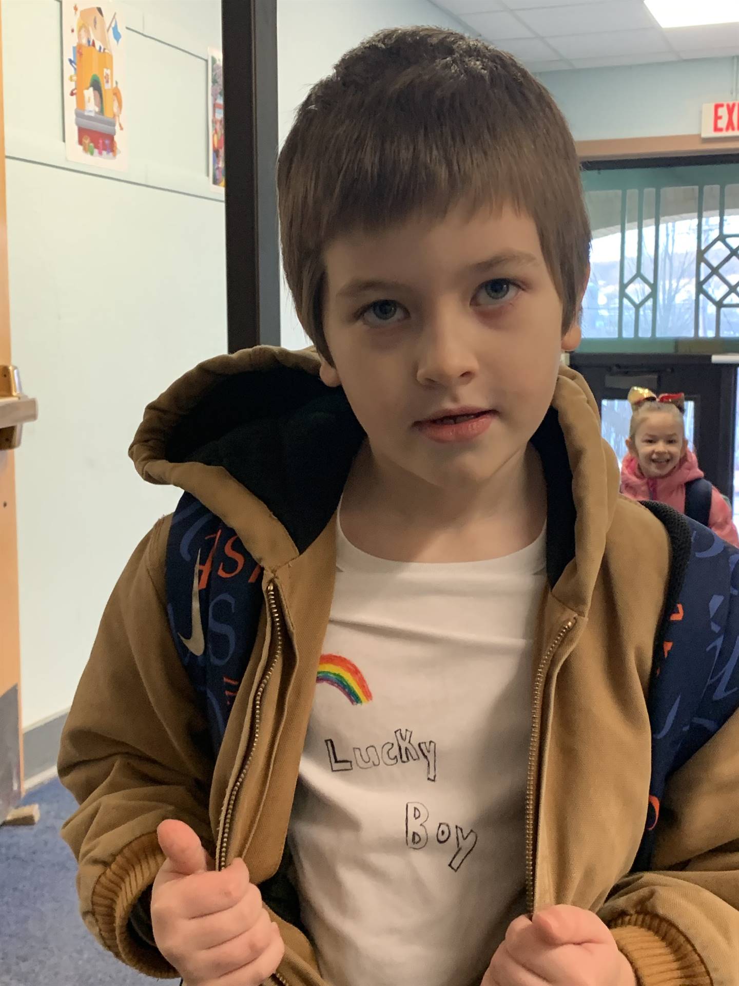 a student shows shirt that says "lucky boy" with a rainbow