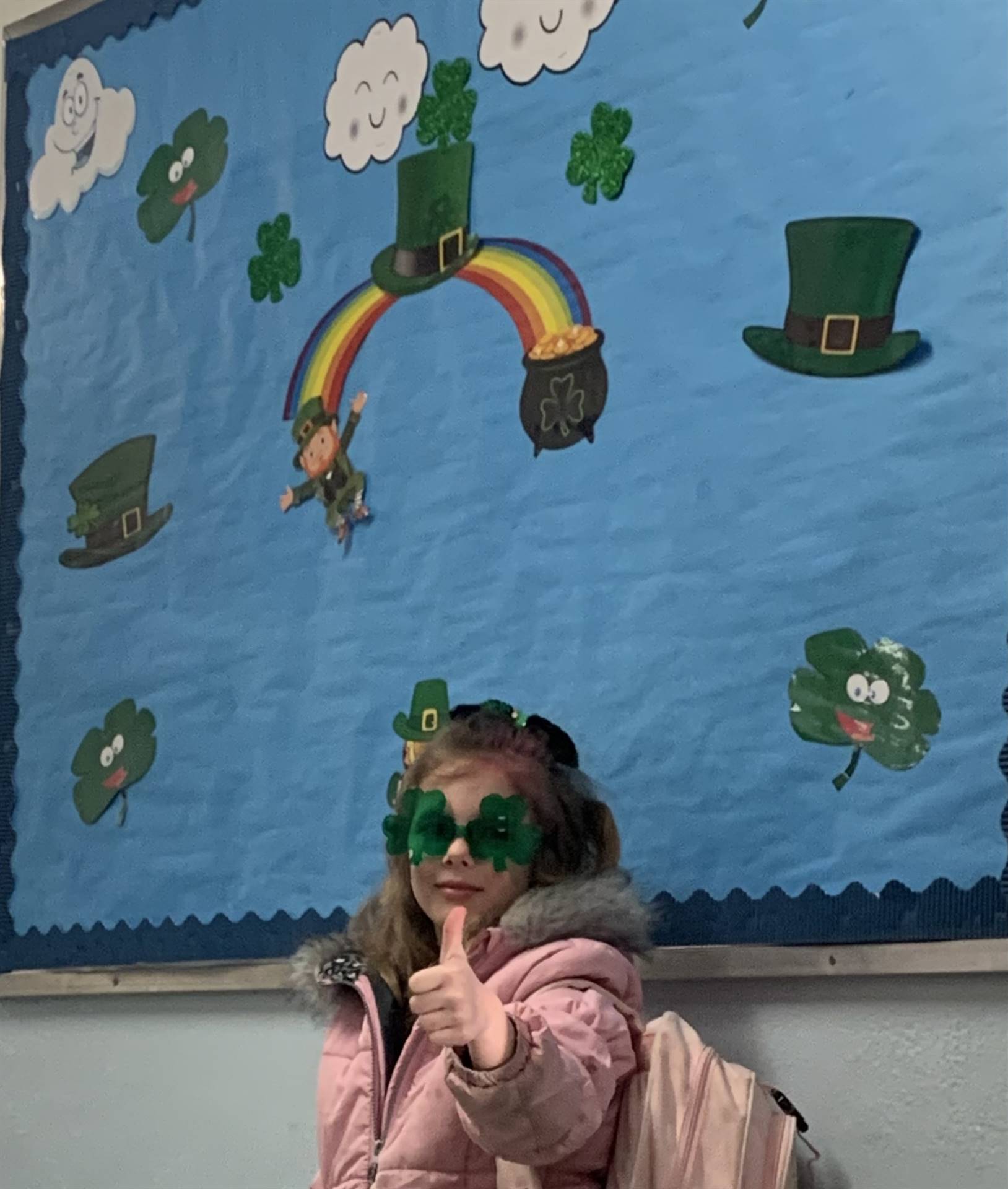 a student with green shamrock glasses gives a thumb up