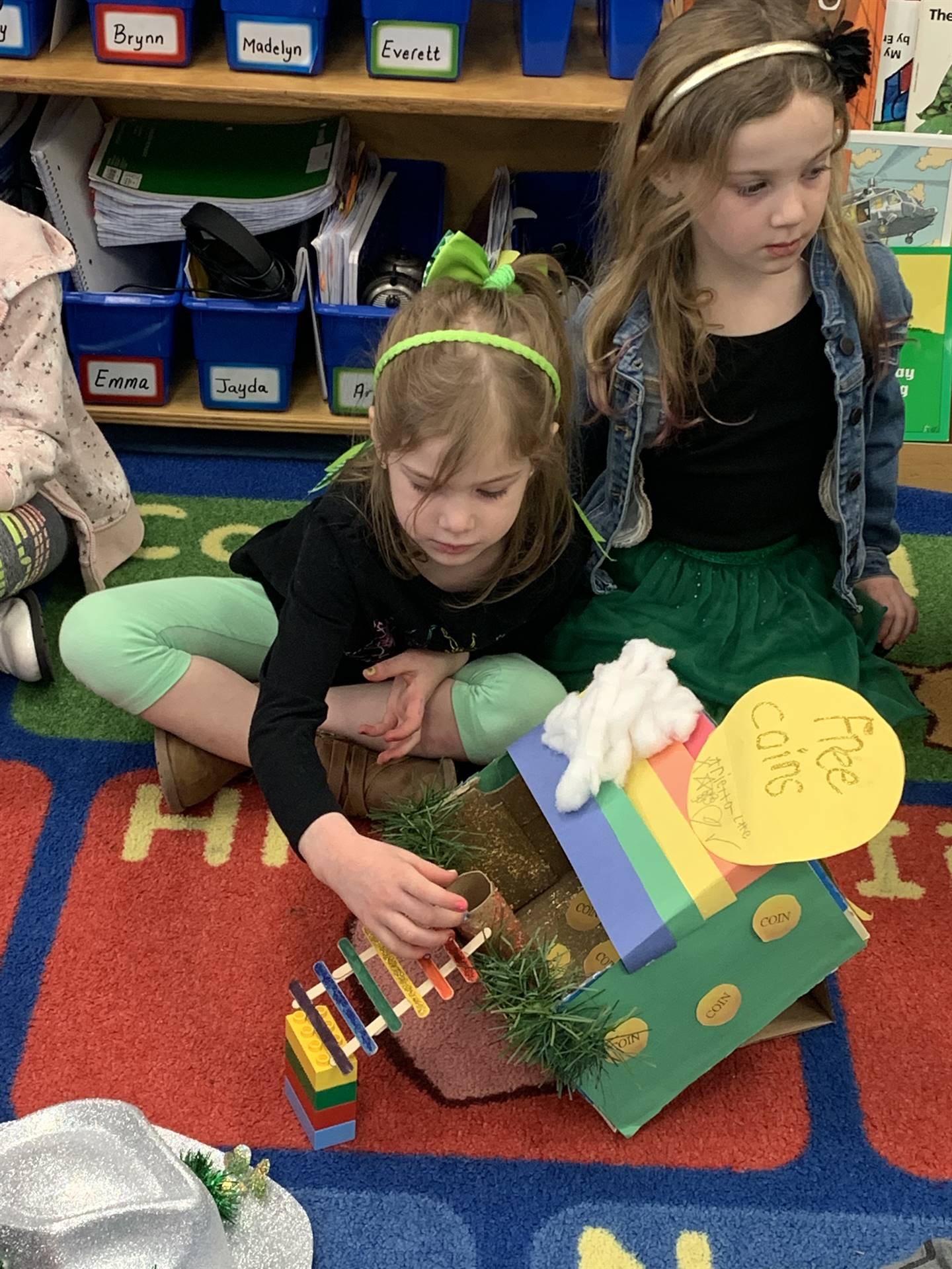 2 students with a  leprechaun trap that has a rainbow ladder that goes to roof. 