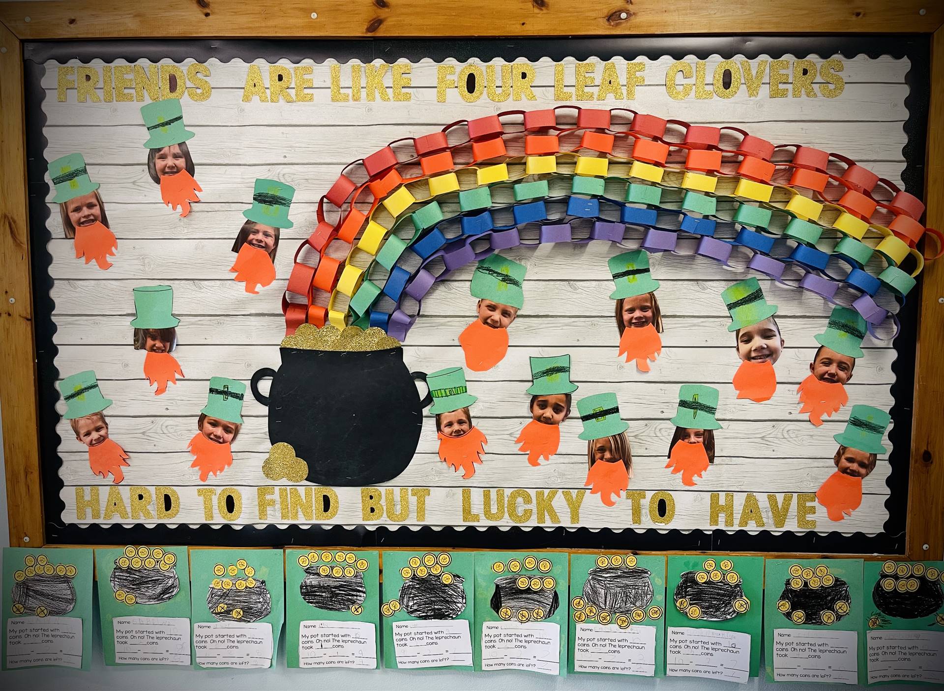 bulletin board with pot of gold and a rainbow going to right and faces of leprechauns all over.