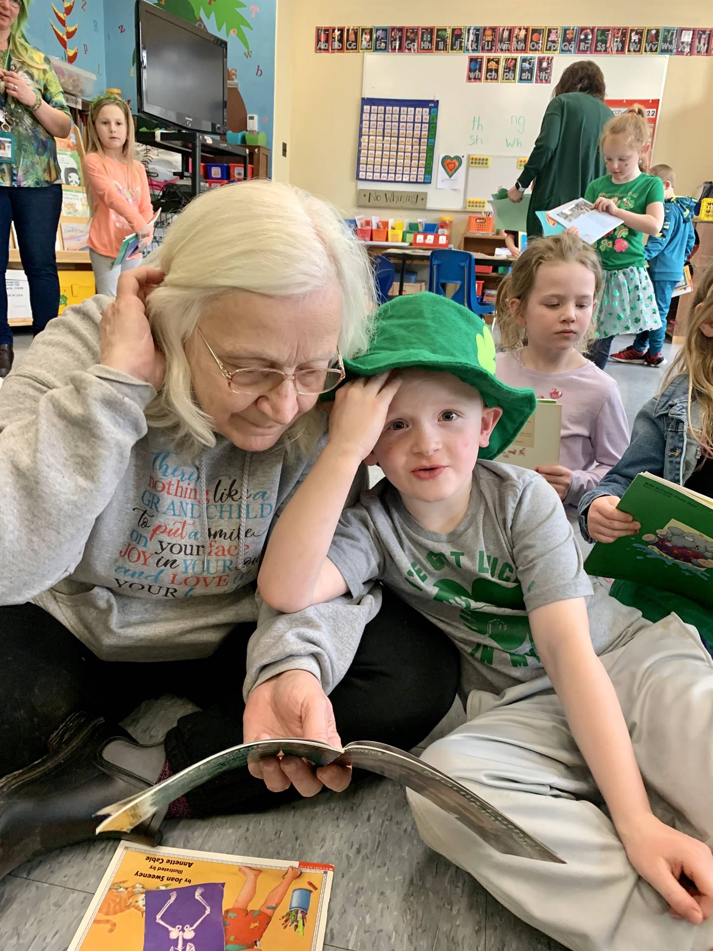 a student in green hat reads with adult.