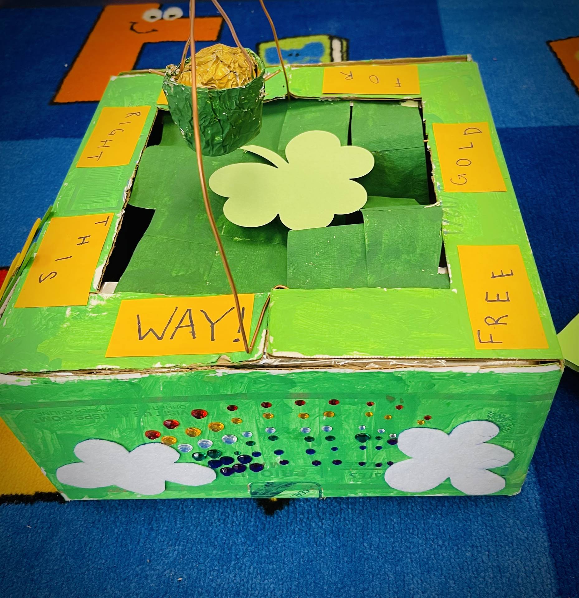 a green leprechaun trap with shamrock and gold on top