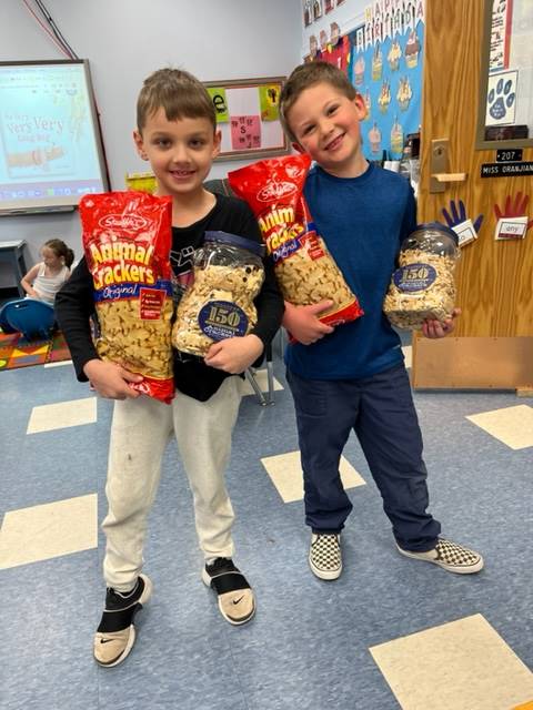 2 students holding up animal crackers.