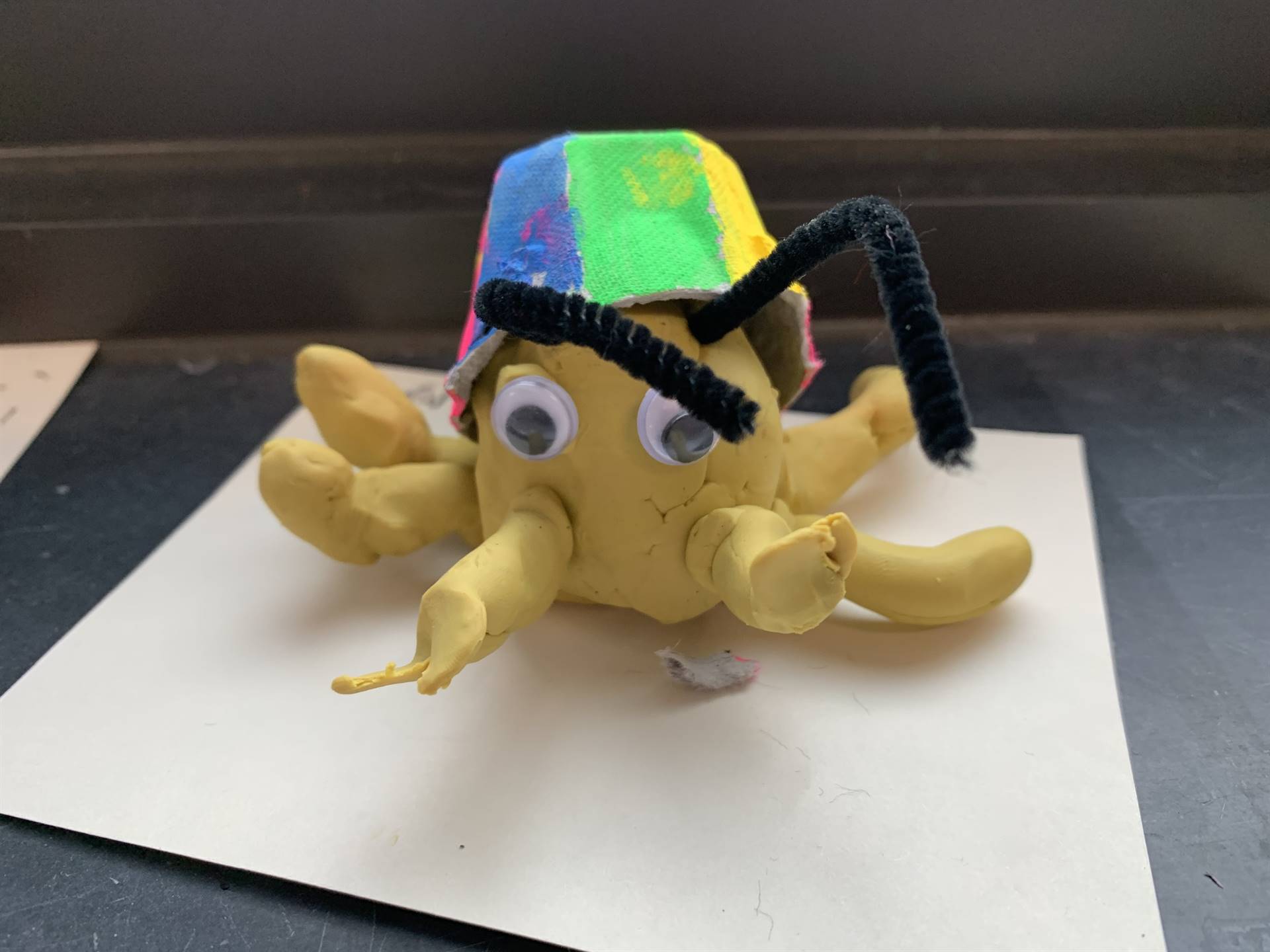 a yellow clay crab with a rainbow shell on its back