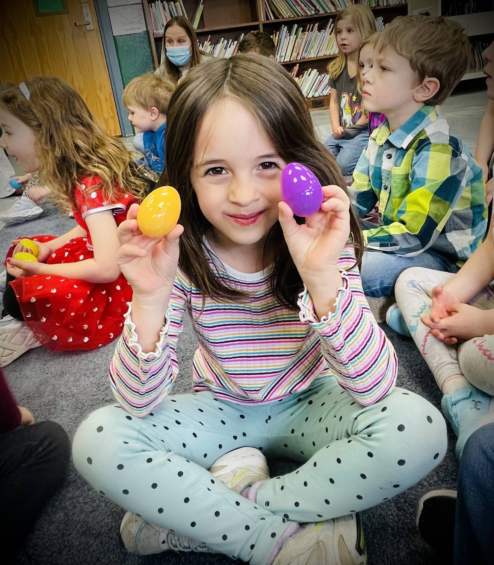 a student holds up a plastic egg in each hand