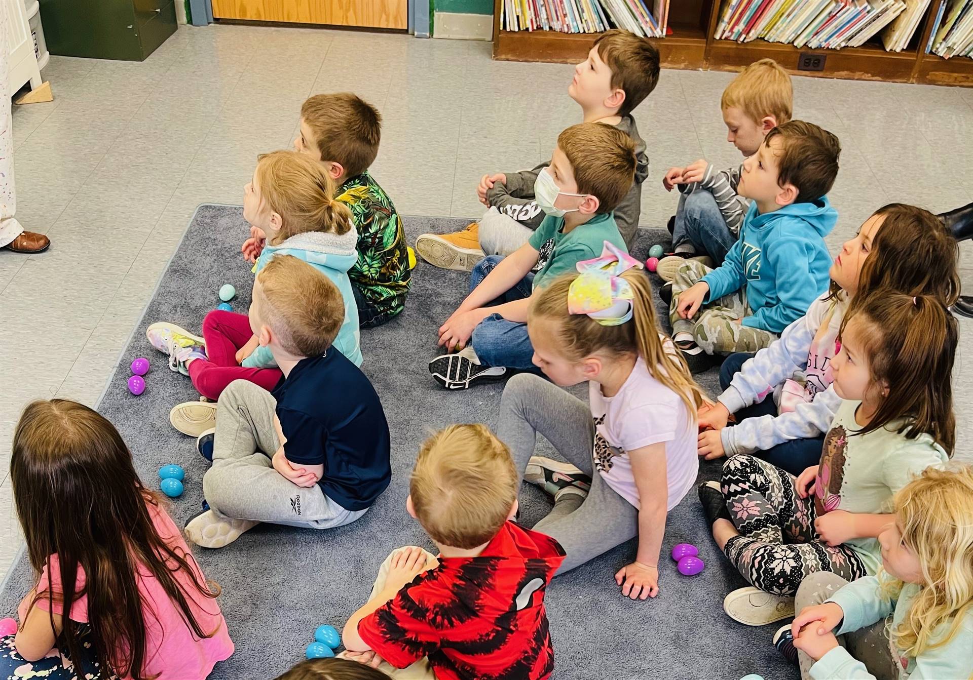 students sit on floor and listen to a spring story .