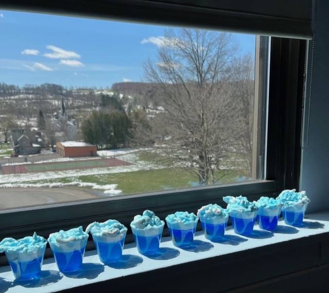 cups filled with blue water and shaving cream floating on top