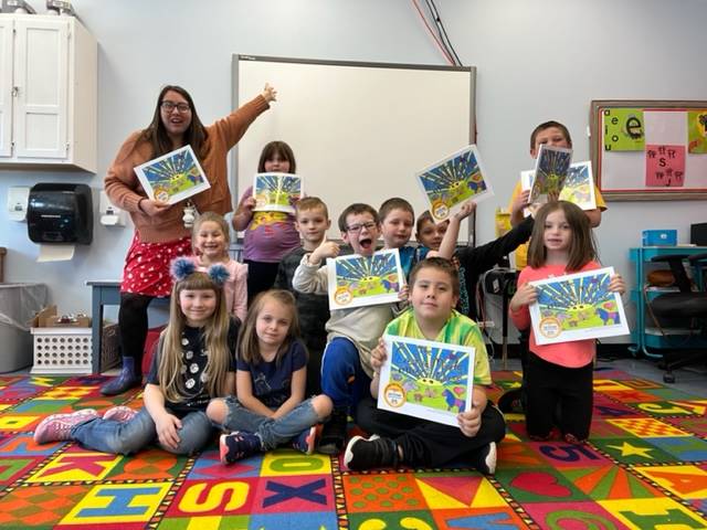 students and teacher holding a picture book they published