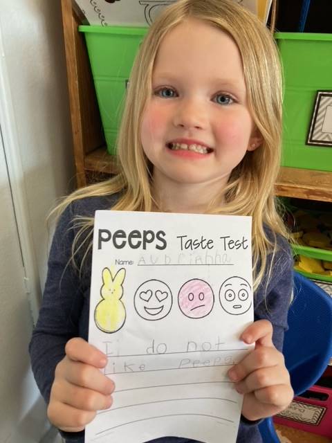child holding up paper of a yellow peep and 3 faces