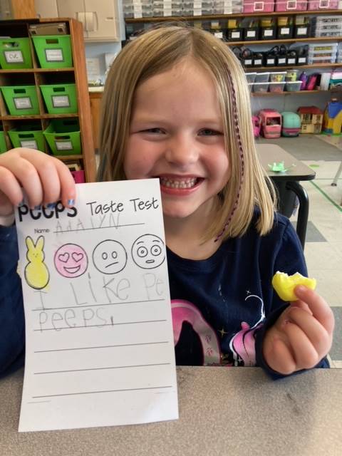 child holding up paper of a yellow peep and 3 faces