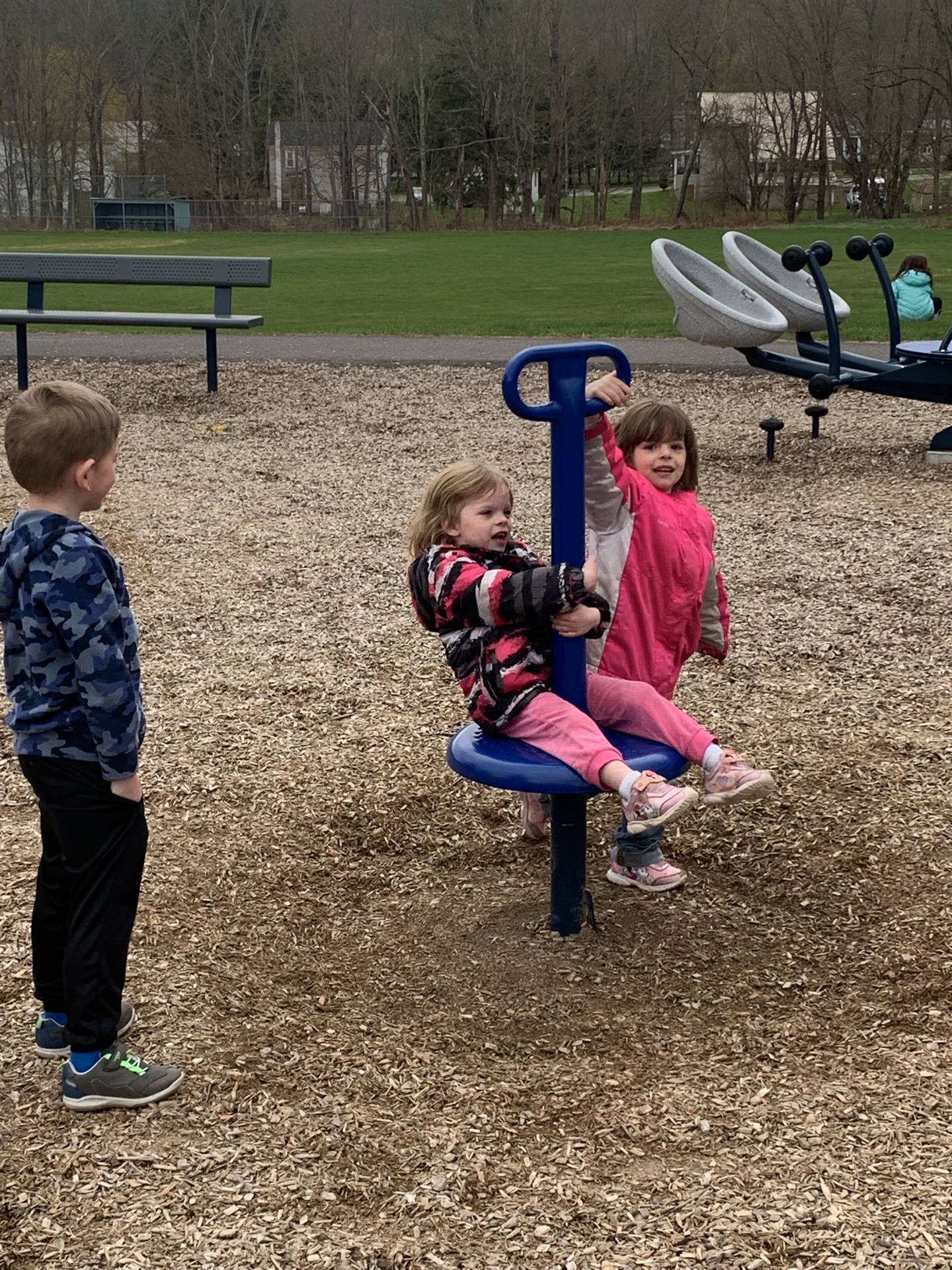 2 children spinning on a playground spinner