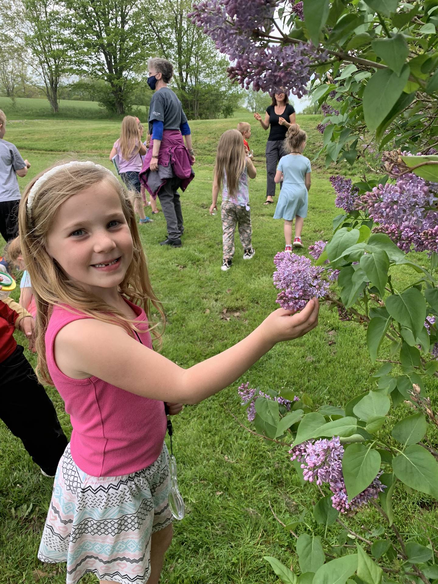 child outside touching lilac