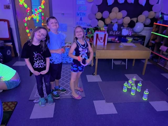 3 students with balloons and glowing decorations in background