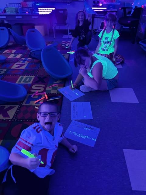 student drawing with highlighters for glow day