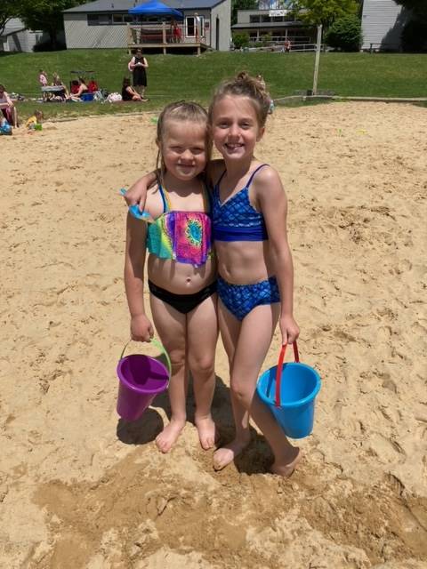 2 students standing in sand with buckets