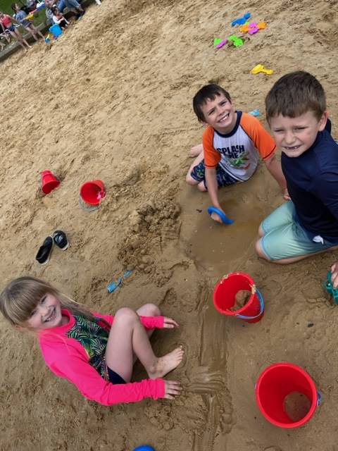 a group of kids playing in sand with buckets and shovels