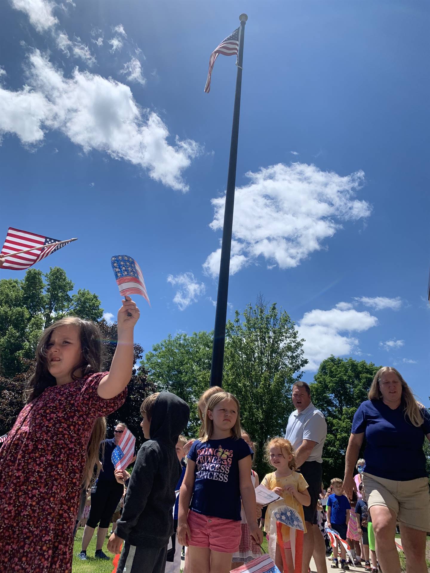 students wave mini flags outside for flag day parade