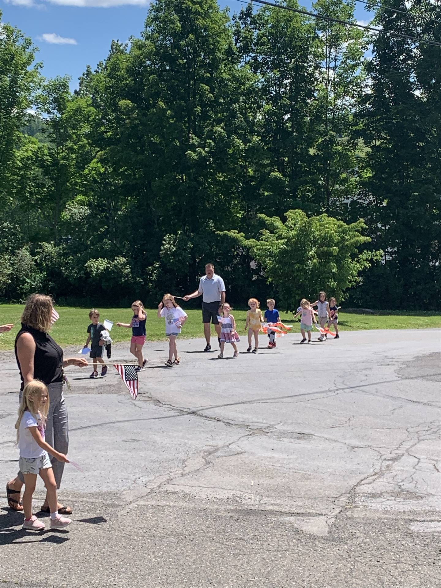 students wave mini flags outside for flag day parade