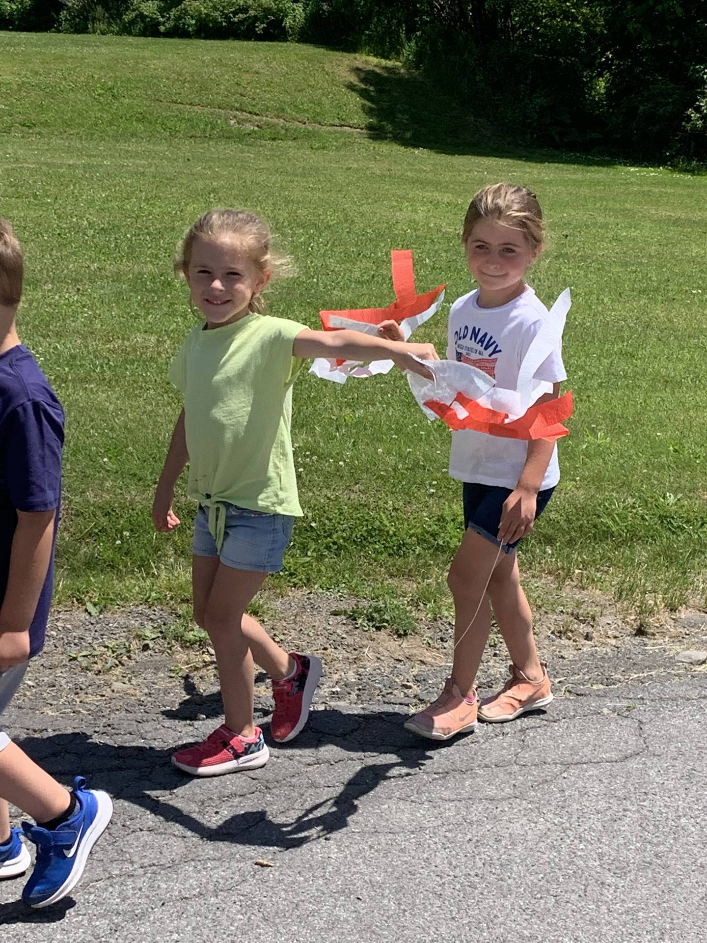 2 students wave mini flags outside for flag day parade