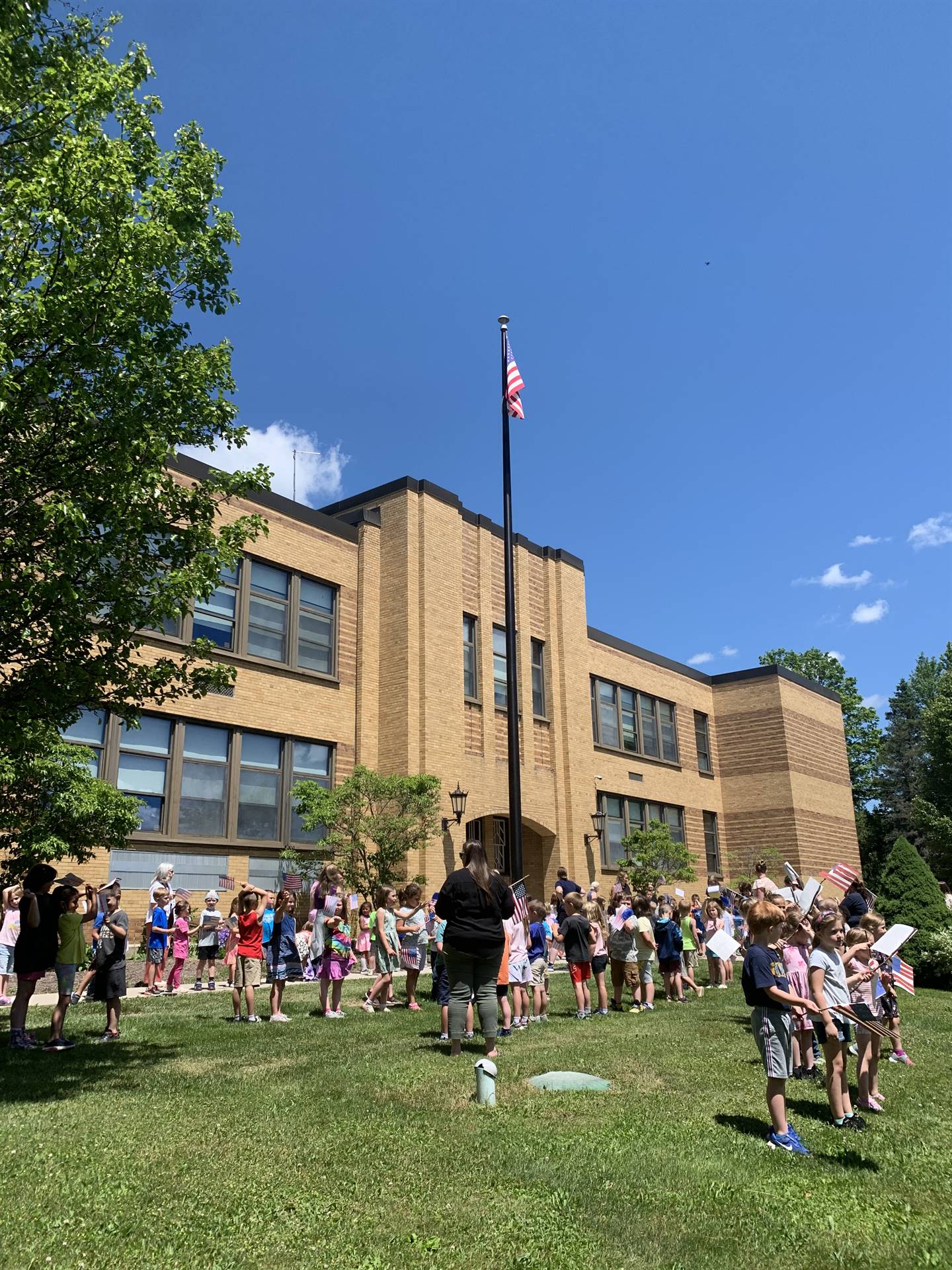 Guilford Elementary school in back ground, students watch as flag is raised
