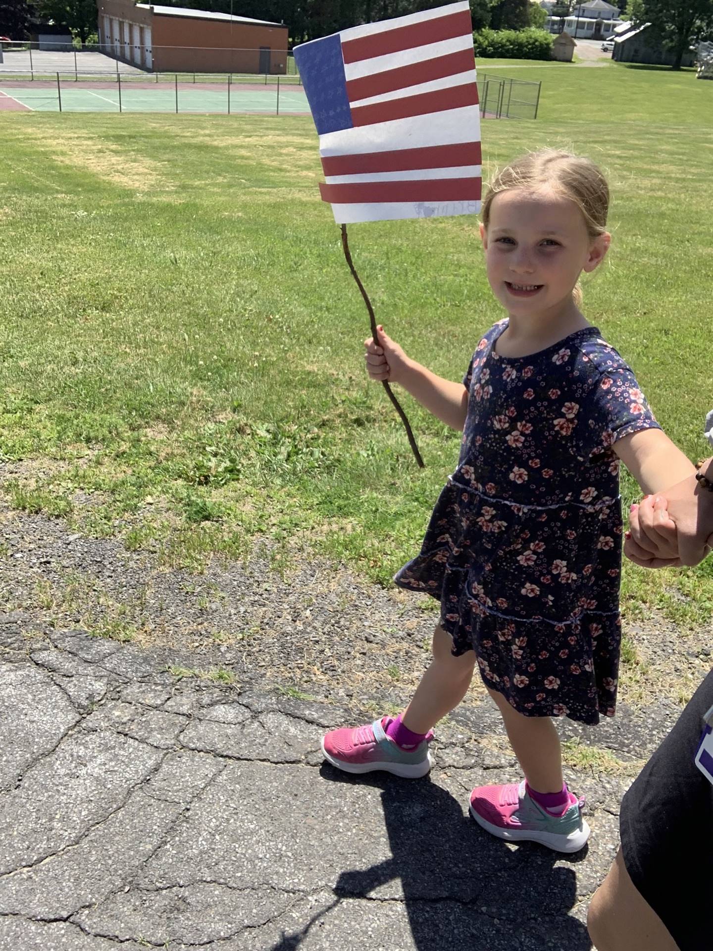 a student waves a mini flag outside for flag day parade